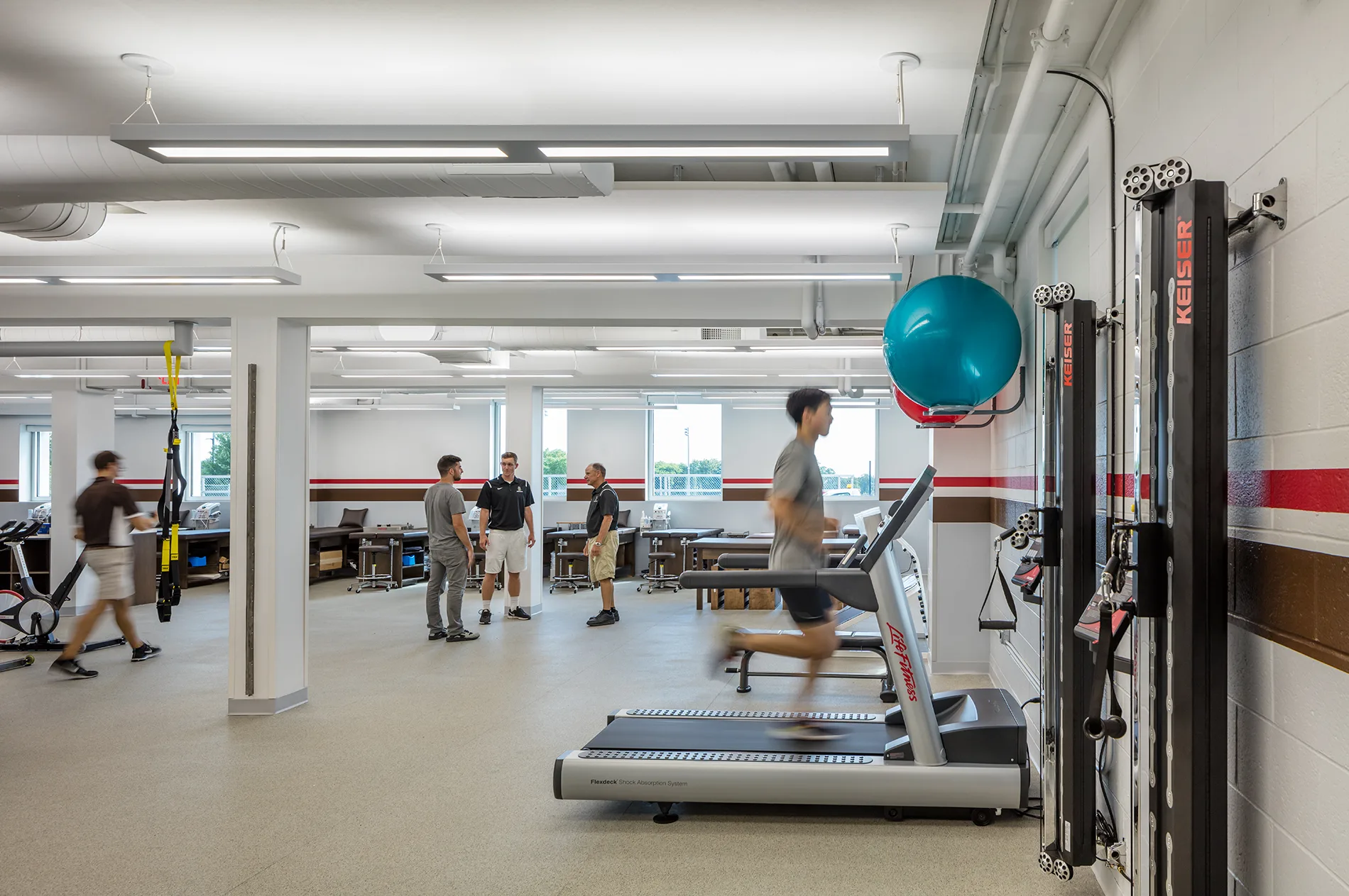 Light-filled athletic training facility with treadmills, therapy stations, and flexible strength-training equipment designed for student athletes.