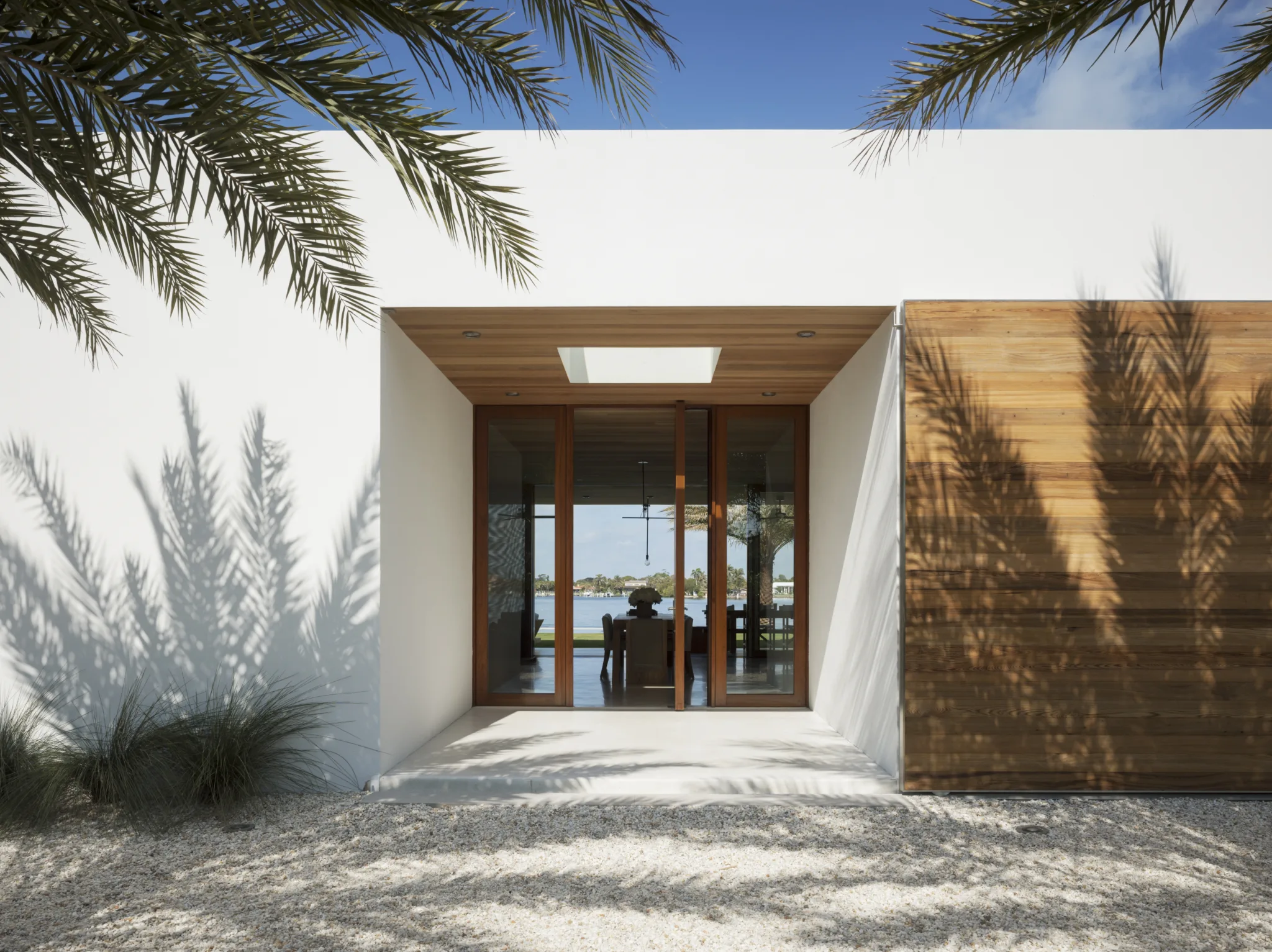 The wide entry to a modern white house in Florida, where you can see right through to the water.