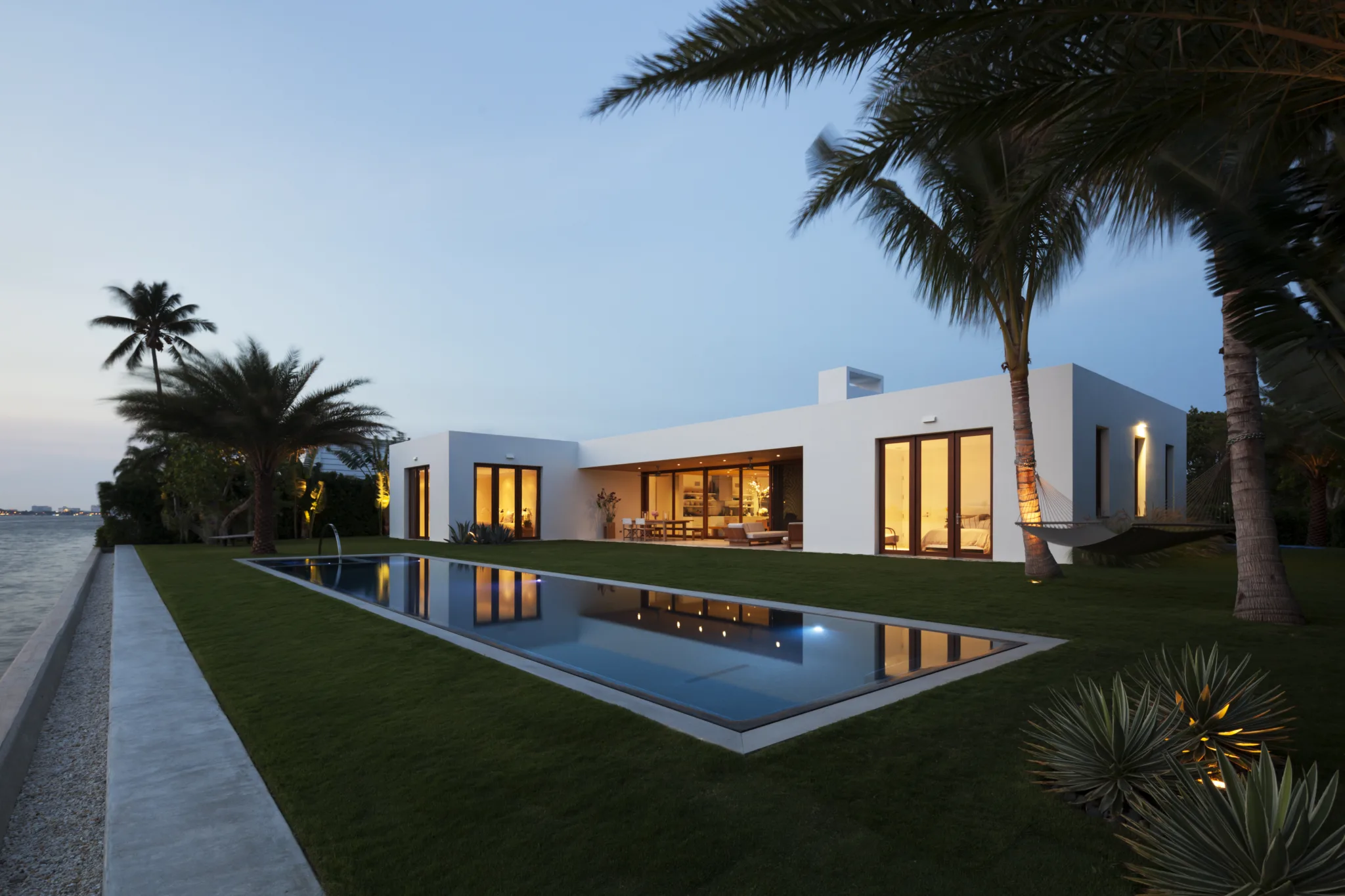 A modern white house in Florida, a single waterfront residence showcasing indoor/outdoor living and a beautiful pool.