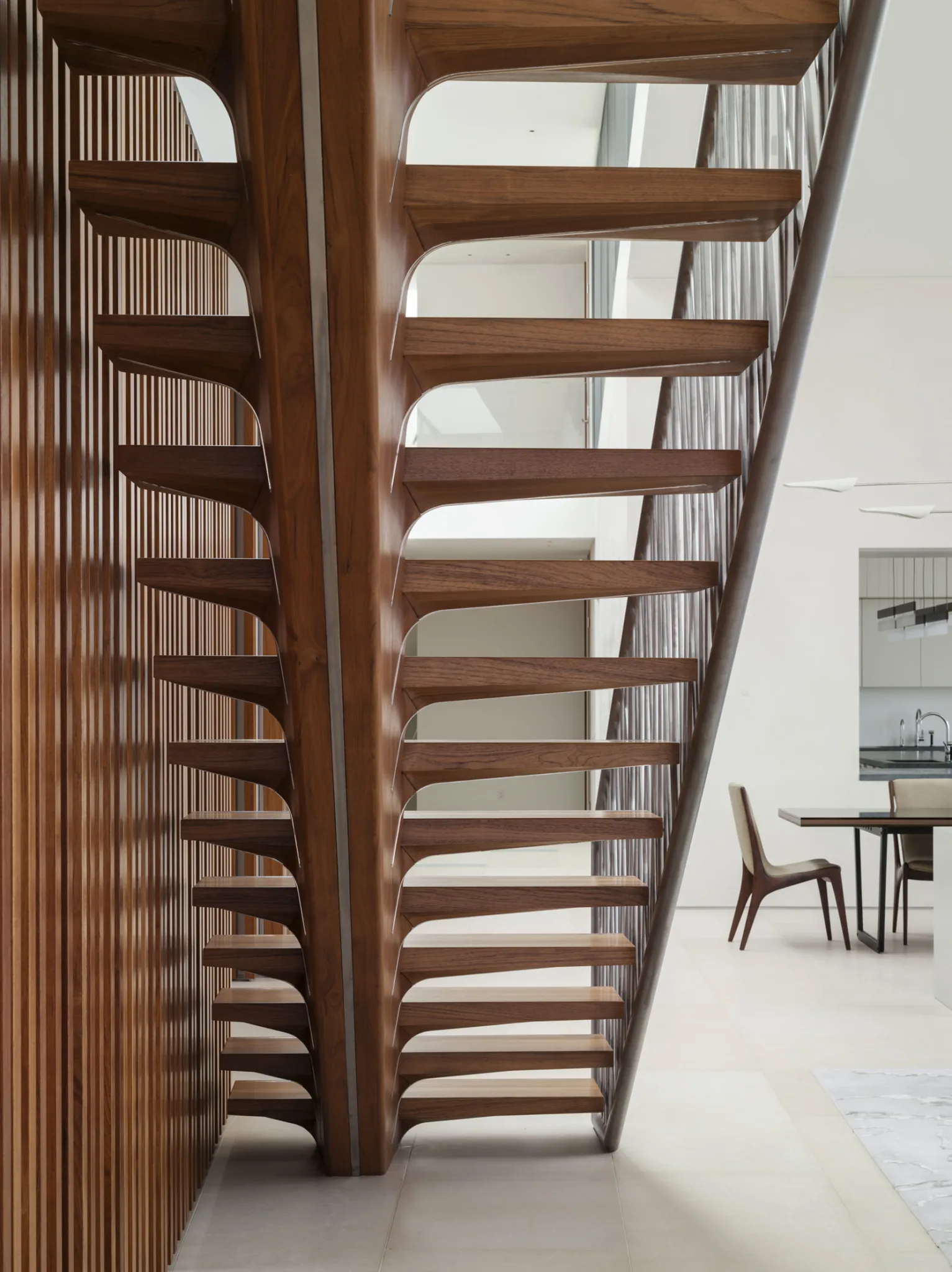 Detail of sculptural wooden staircase with open risers, emphasizing craftsmanship and architectural geometry.
