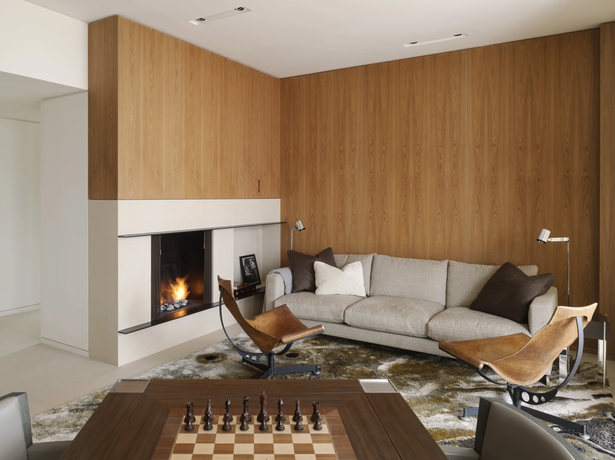 Sophisticated lounge with wood-paneled walls, fireplace, and modern furniture for a refined and cozy interior.