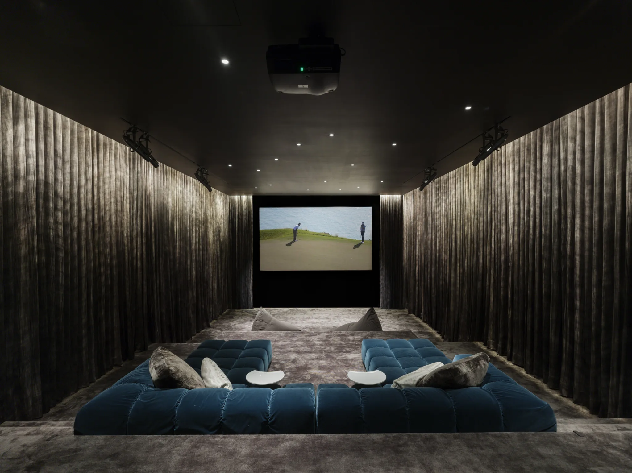 Private home theater with plush sectional seating, velvet walls, and cinematic lighting for an immersive experience.