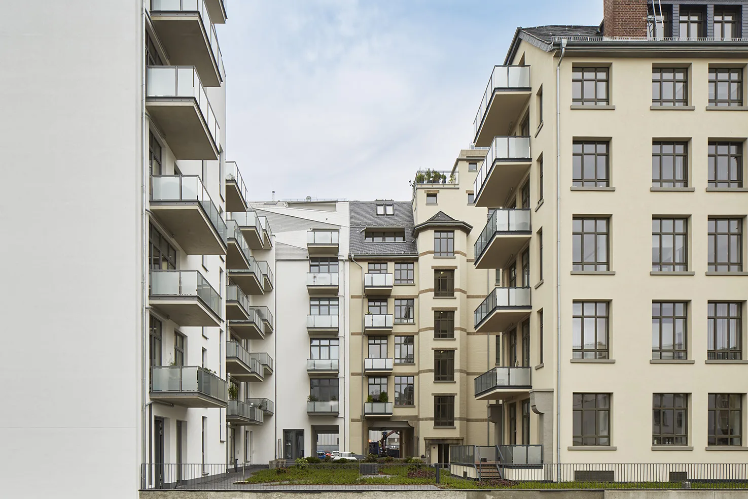 Courtyard view of the East Side Lofts in Frankfurt, featuring a mix of historic and modern facades with glass balconies and a landscaped central garden.