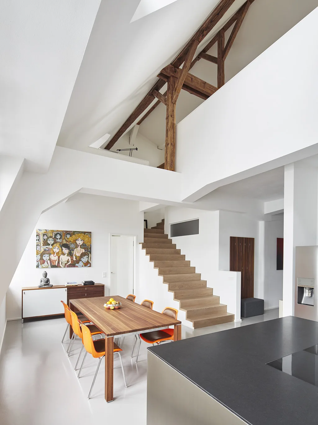 Loft dining area with exposed beams, wood stair, and colorful artwork.