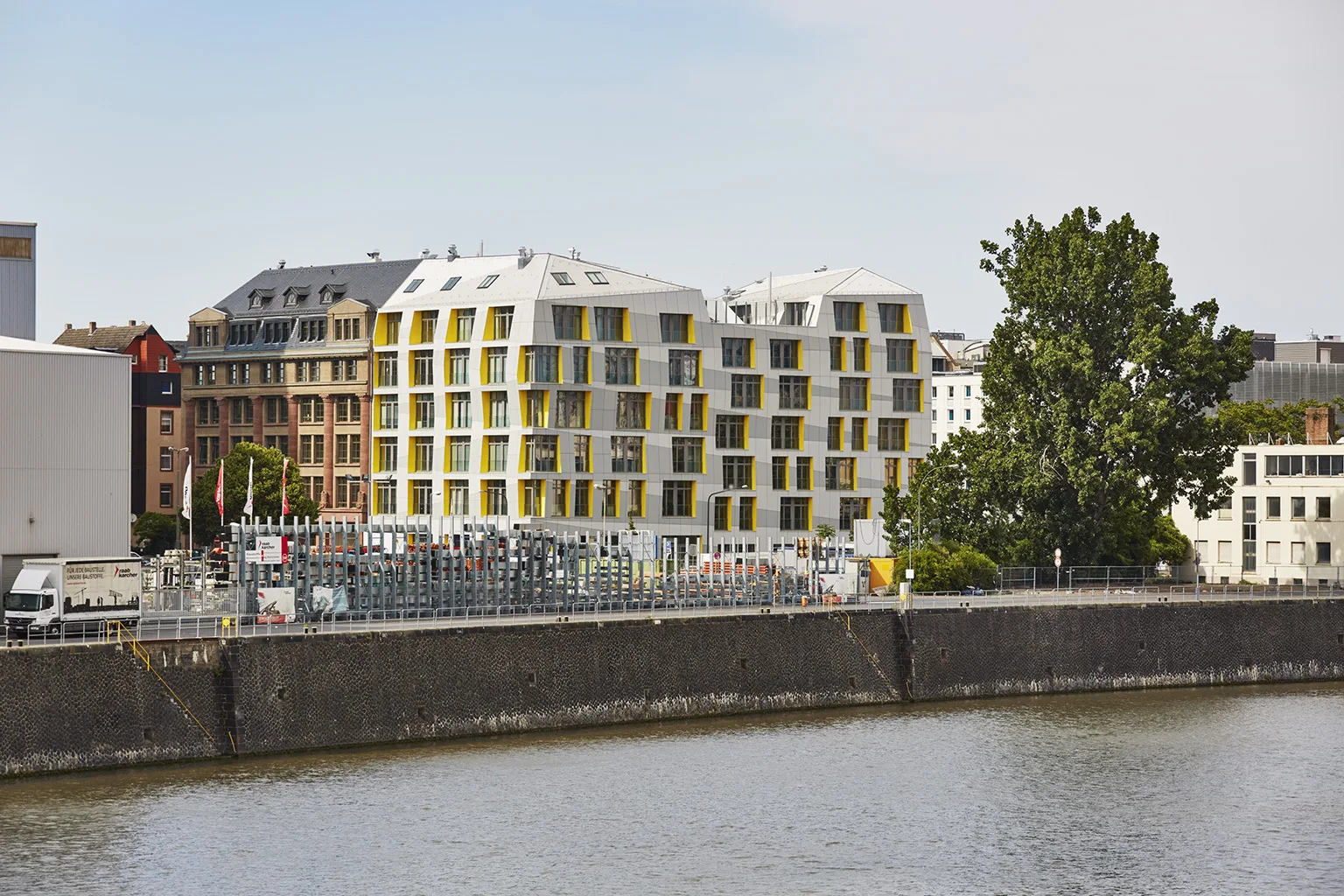 East Side Lofts in Frankfurt with white façades accented by bold yellow window frames, contemporary architecture overlooking the river.