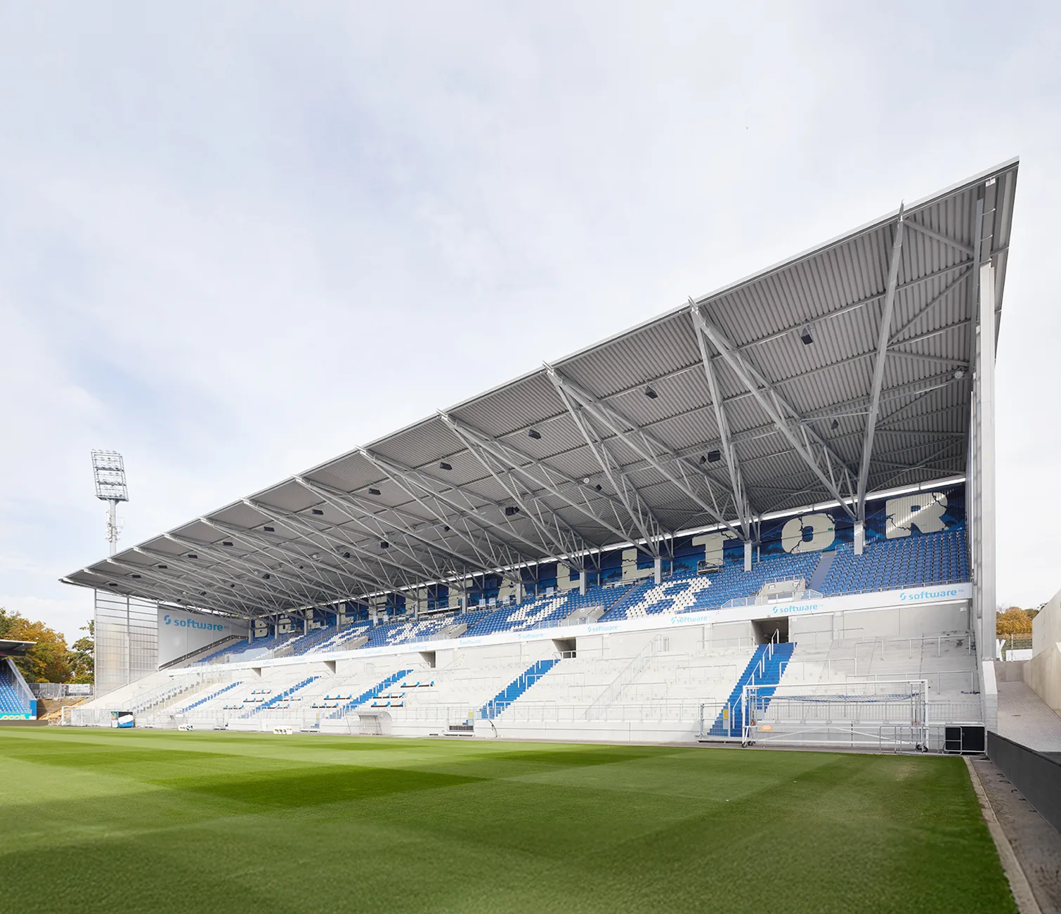 Angled perspective of the grandstand with covered seating, highlighting the extensive roof structure and blue-and-white seating arrangement.