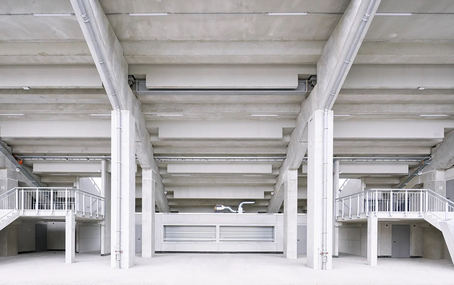 Concrete concourse beneath stadium seating with open walkways and stair access.