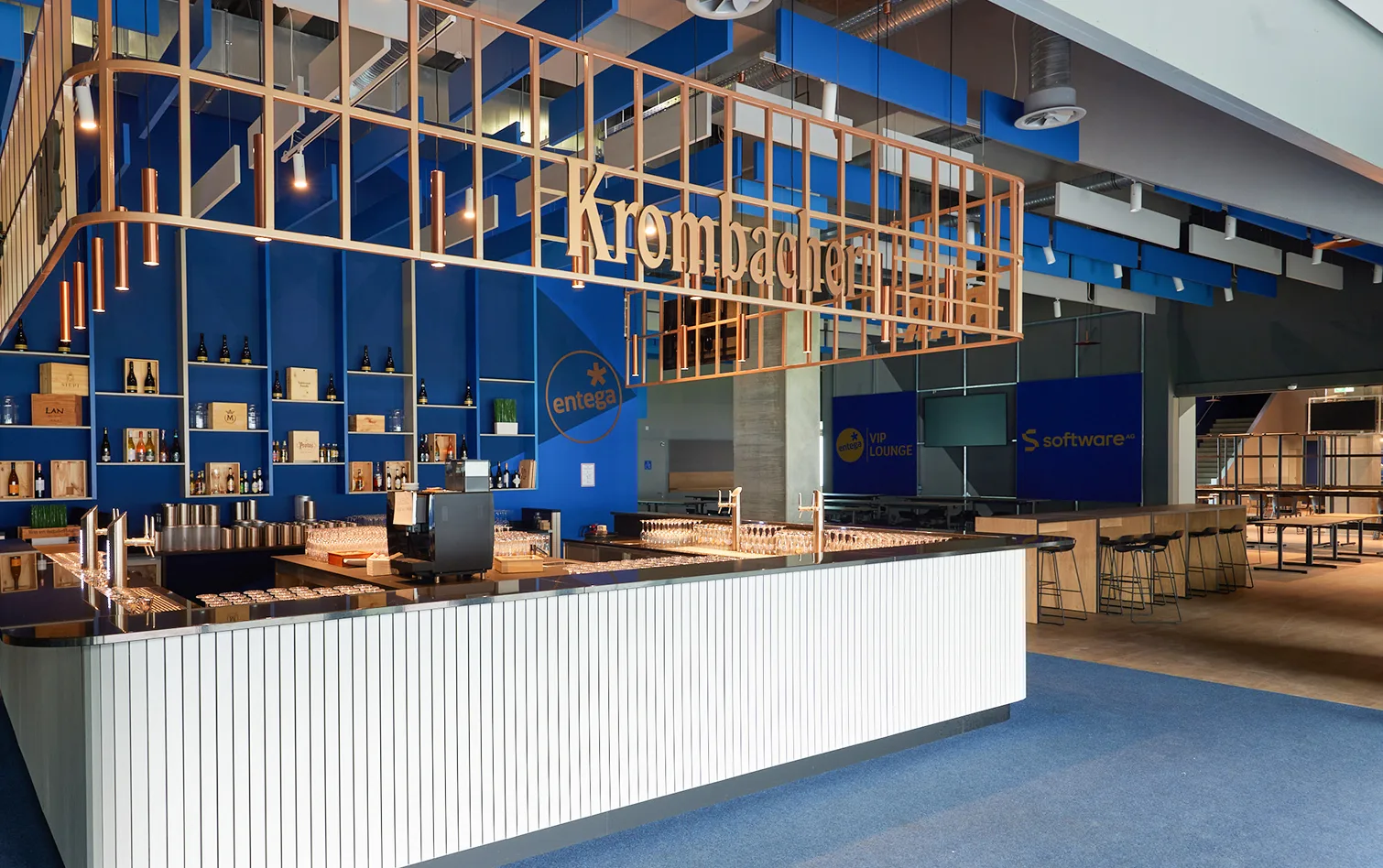 Modern concession bar with blue branding, wooden shelving, and gold signage under exposed ceilings.