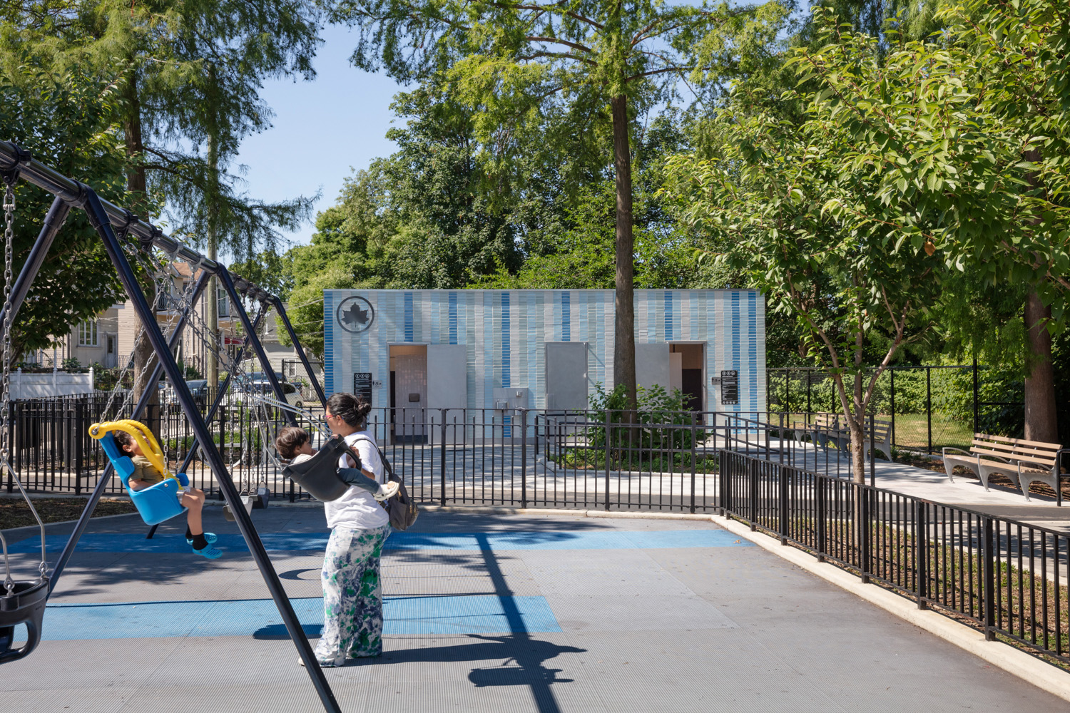 1100 Architect–designed comfort station with blue-striped tile façade, blending modern design with park surroundings to provide accessible amenities for families and visitors.