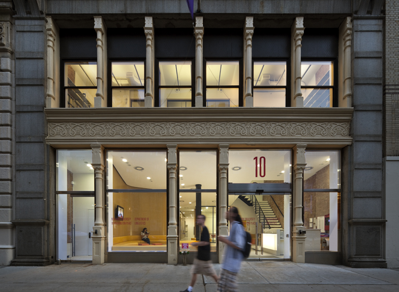Front façade of a restored academic building featuring large display windows at the ground floor and a rhythm of arched and rectangular openings above.