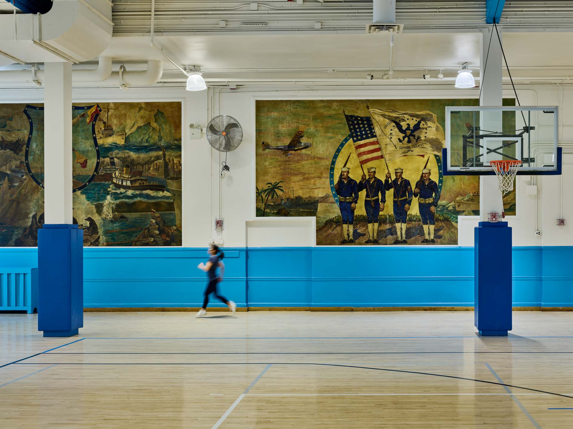 Historic WPA murals preserved alongside renovated NYC Parks basketball court with blue accent columns.