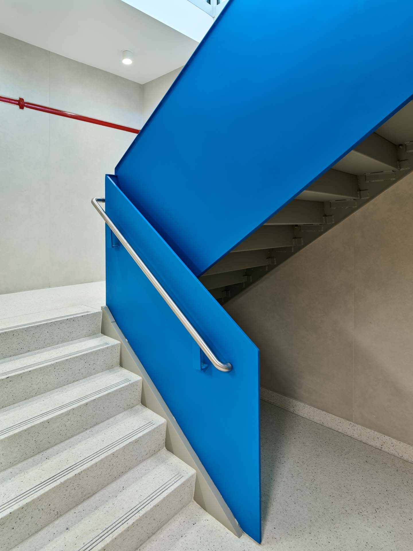 Terrazzo stair with bold blue painted stringer and stainless steel rail in renovated NYC Parks recreation building.